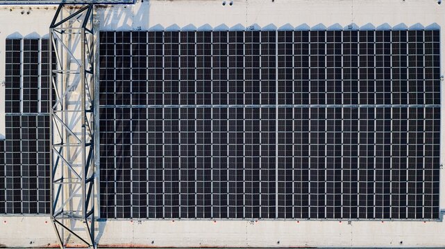 Aerial view of a large array of solar panels installed on a flat industrial rooftop in Delft, South Holland, Netherlands.