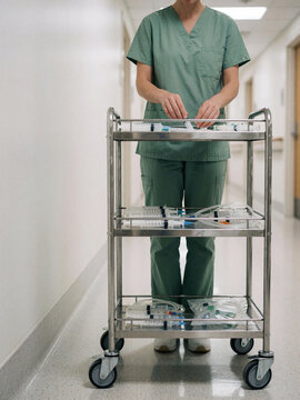Nurse preparing syringes on a medical trolley in a hospital corridor