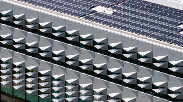 Aerial view of a modern building facade with geometric sun-shading panels and rooftop solar arrays in Delft, South Holland, Netherlands.