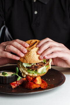 Restaurant Guest Holding Gourmet Burger with Both Hands Before Taking a Bite