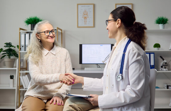 Doctor and patient share a handshake in clinic. The senior woman ends a consultation as the healthcare provider offers support and explains results clearly. Clear symbol of trust and care.