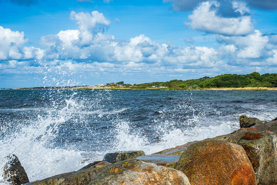 Gischt von anbrandenden Wellen spritzt &uuml;ber die Steinkrone der Mole von Torekov, Schonen, Schweden.