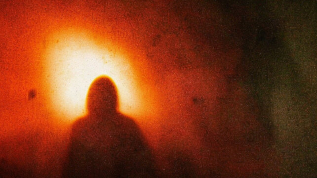 Mysterious Dark Figure Emerging from Fiery Red Light in Vintage Horror Scene