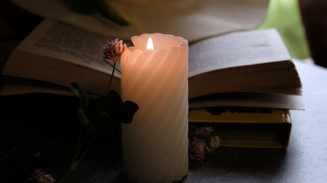 Candlelight in the dark, flowers and reading book. Cozy evening at home.  Burning candle