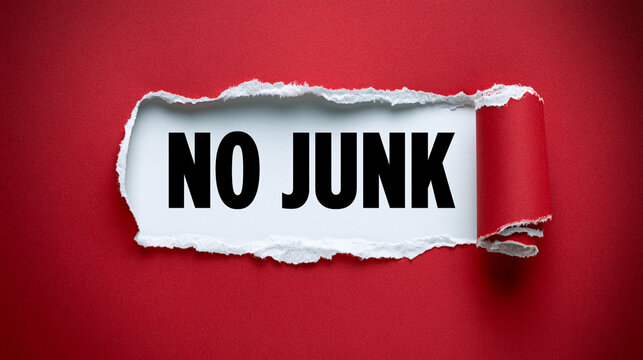 The words no junk written on a white paper background behind a torn red paper