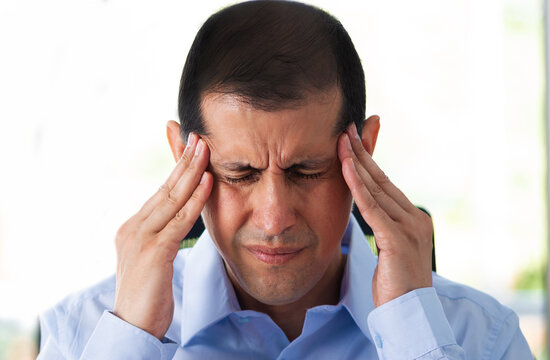 Sick executive with migraine complaining in pain rubbing temples at office.