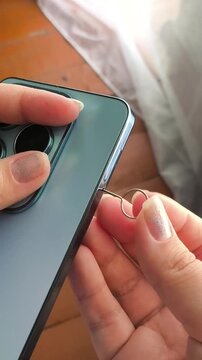 Woman opening smartphone SIM tray with SIM ejector tool, SIM card installation, mobile connectivity and cellular network concept.