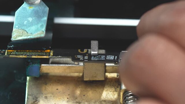 Detailed view of skilled tech removing electronic connector with solder iron in workshop