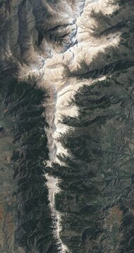 Bird's eye view on mountain ridge covered with snow. Camera is moving forward. Vertical video. Animation based on image by NASA