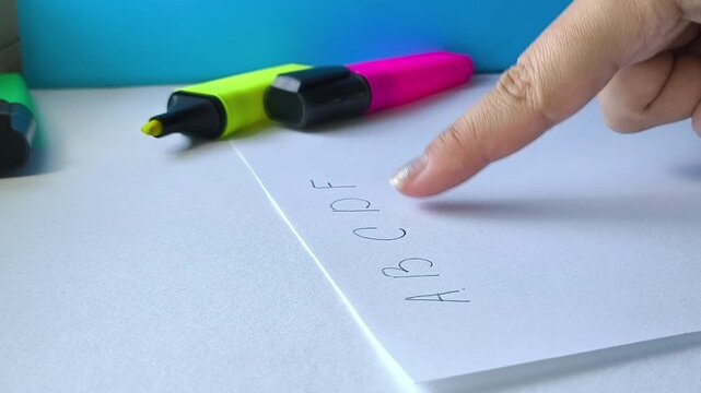 Teacher pointing to English alphabet letters on paper, teaching children to read, literacy and language learning concept.