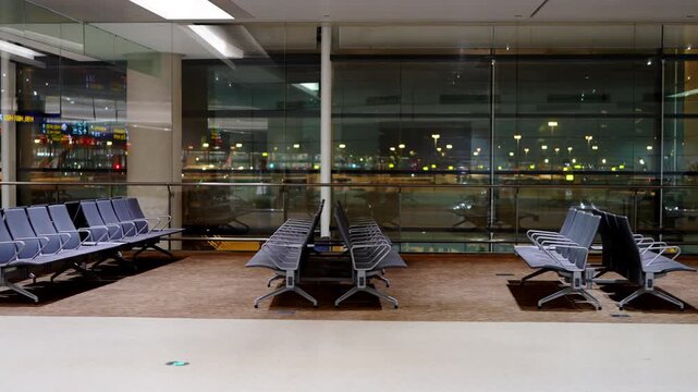 An empty modern airport waiting lounge with arranged seats, large glass windows, and interior space for travelers.