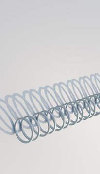 A metal coil casting repeating shadows on a white background