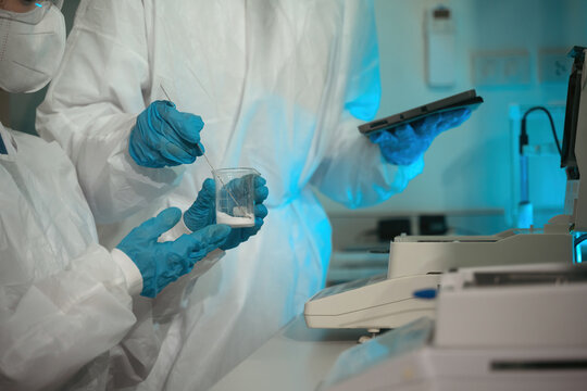 Close up of Scientists in Protective Suits Using Moisture Analyzer for Pharmaceutical Quality Control Research in Laboratory