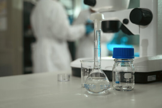 Laboratory Glassware with Volumetric Flask and Microscope During Quality Control Research in Pharmaceutical Lab