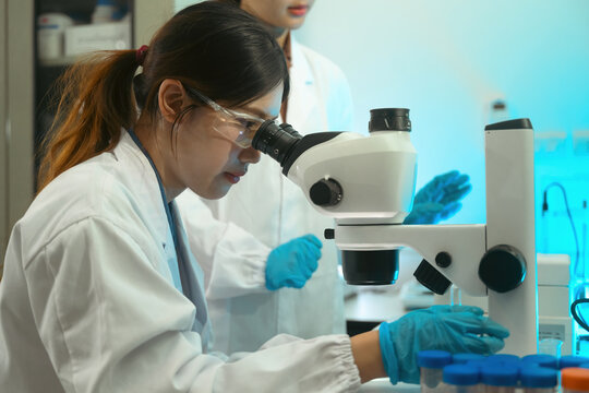 Female Scientist Examining Sample Through Microscope in Modern Research Laboratory