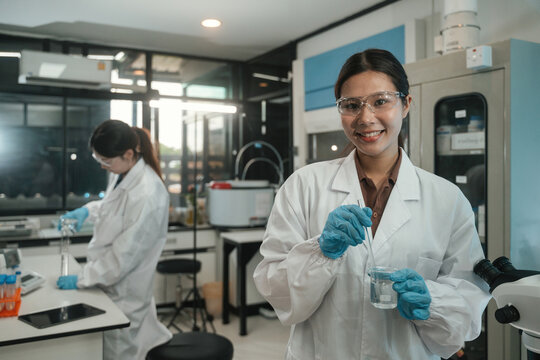 Asian Female Scientists Conducting Research Experiment with Components in Modern Laboratory