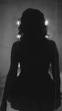 Black and white film color shadow silhouette retro lady back rear view walking in dark room fool smoke go to mirror. sexy woman burlesque old style. flapper girl 20s roaring twenties. vertical video
