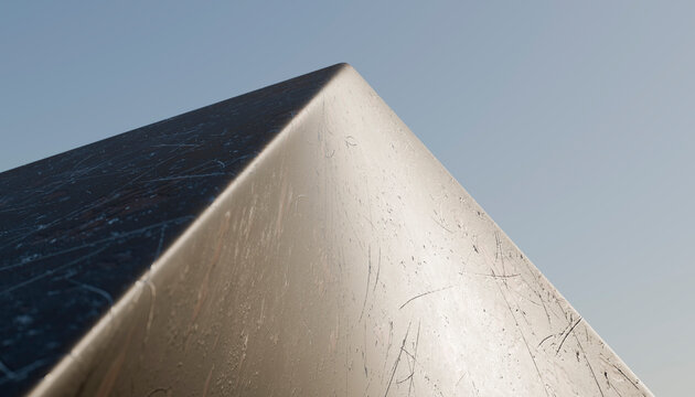Close-up of a scratched shiny metal corner reflecting light outdoors
