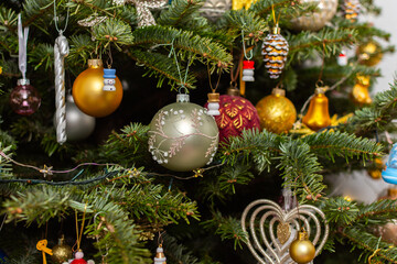 Fototapeta premium A Christmas tree stands with many colorful ornaments hanging from its branches. Each ornament shows different shapes and colors, celebrating the festive season and bringing joy to the home
