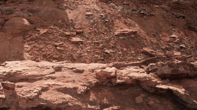 A large area of rocky terrain is visible at a construction site. Various sizes of stones and earth layers are scattered around. Machinery and tools may be present nearby as work continues.