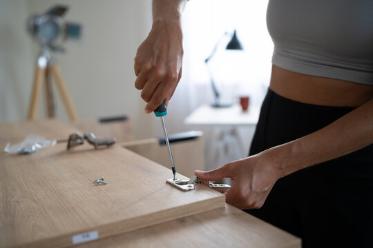 White Person assembling furniture by attaching a metal hinge