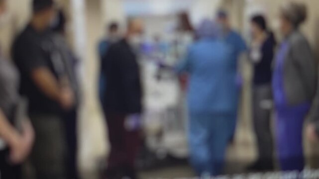 Medical staff moving patient on stretcher through crowded hospital corridor, blurry emergency scene