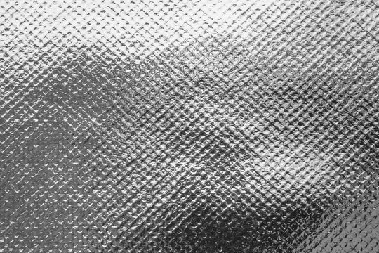 Silver foil texture background with embossed diamond pattern and shiny metallic surface reflection