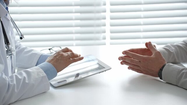 Medical professional using a digital tablet during a healthcare consultation. Discussing diagnosis and treatment plan with a patient in a modern clinic setting
