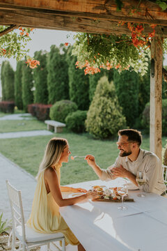 Couple enjoying a romantic meal in a serene garden setting during sunset