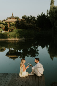 Romantic evening by the serene lake during sunset with two glasses raised