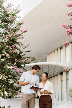 Couple reading together under blooming trees at a modern architectural site