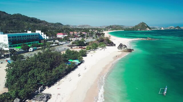 Stunning overhead panorama of Kuta Lombok coastline featuring tropical shoreline palm trees and crystal clear sea under blue sky