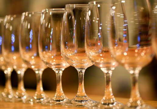 A row of neatly arranged empty wine glasses, inside the bar