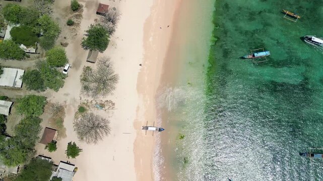 Drone view of Pink Beach Lombok showing coral fragments, green hills, and clear waters