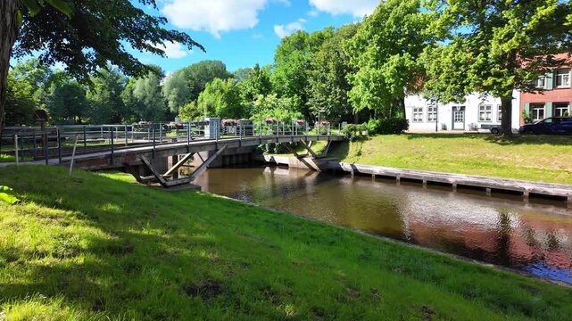Small bridge over an idyllic canal with green banks and historic houses in Friedrichstadt. Historic houses,waterways and lush greenery combine traditional urban architecture with a natural environment