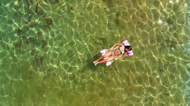 Stunning overhead drone perspective capturing her serene moment of summer bliss against the vast expanse of the pristine ocean