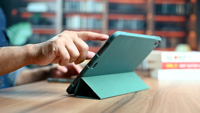 Diligent student person read digital tablet, learn university research topics, read device hand near library interior bookshelf shelf, background bookshop store stack school college learn read.