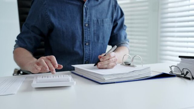 Man analyzing financial documents and calculating taxes, handling a large pile of paperwork and budgeting personal finance for business accounting or administrative tasks