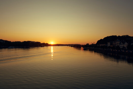 River sunset over a European waterfront town with reflection on calm water and riverside street