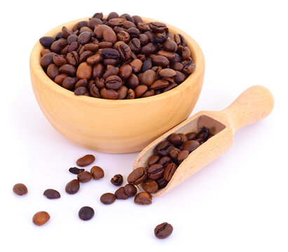 Roasted coffee beans in a wooden bowl with a scoop isolated on a white background.