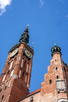 Brick tower and ornate sundial of the Main Town Hall rise under the sky in Gdansk, Poland, displaying Gothic and Renaissance architecture.
