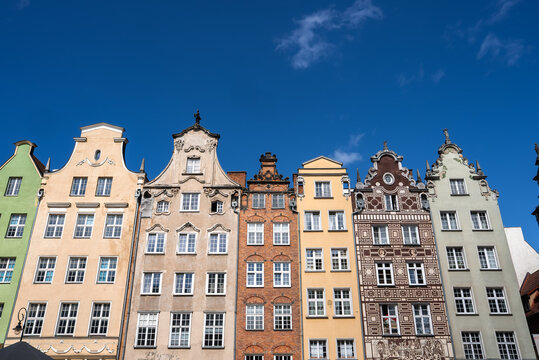 Row of traditional ornamented historic tenement house facades stands under a clear sky in the old town district of Gdansk, Poland.
