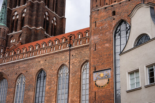 A detailed view of the brick gothic exterior and sundial at Saint Mary Church, located in the historic old town district of Gdansk, Poland.