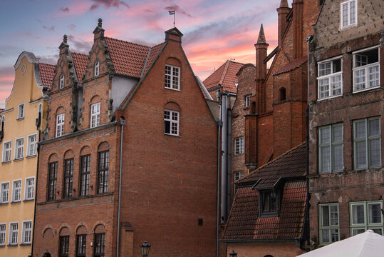 Historic brick townhouses and architectural details stand against a sunset sky in the old town area of Gdansk, Poland, showing traditional European heritage.