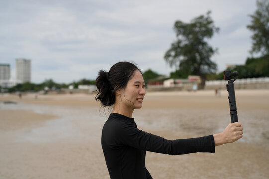 Female travel vlogger filming herself with a handheld gimbal camera