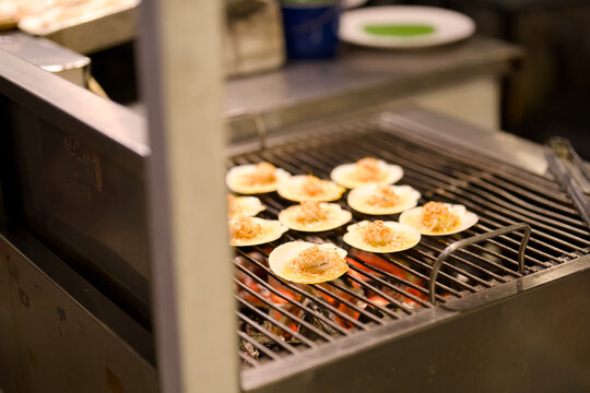 Scallops on the half shell grilling over open flames