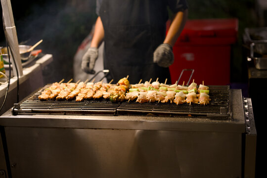 Chicken skewers grilling on a charcoal barbecue at a night market