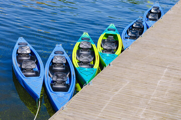 Fototapeta premium Colorful Tandem Kayaks Moored Beside a Wooden Dock on a Calm Lake