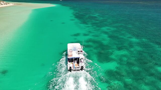 Panoramic aerial view of Coral Bay coast with a boat gliding across the tropical turquoise ocean
