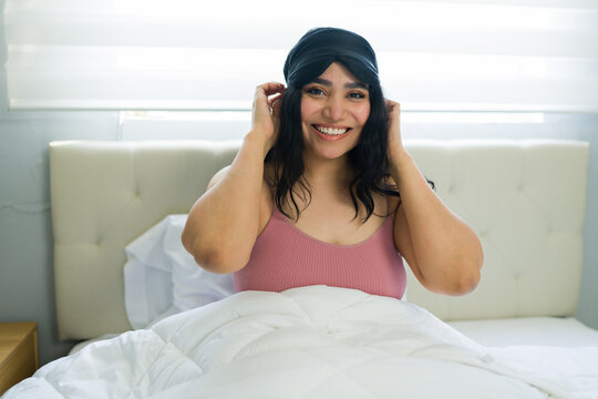 Happy woman waking up removing sleep mask in bed feeling comfortable and refreshed starting morning routine